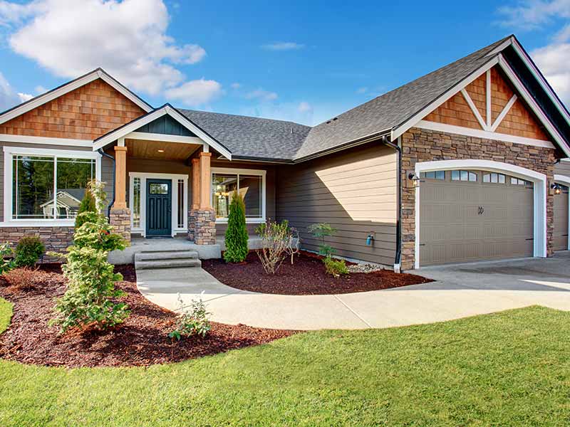 Front side of modern, mid-class home with a stone walkway and gray shingle roof