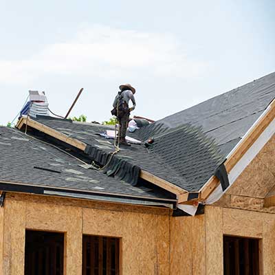 Worker installing new gray shingles on a newly constructed home